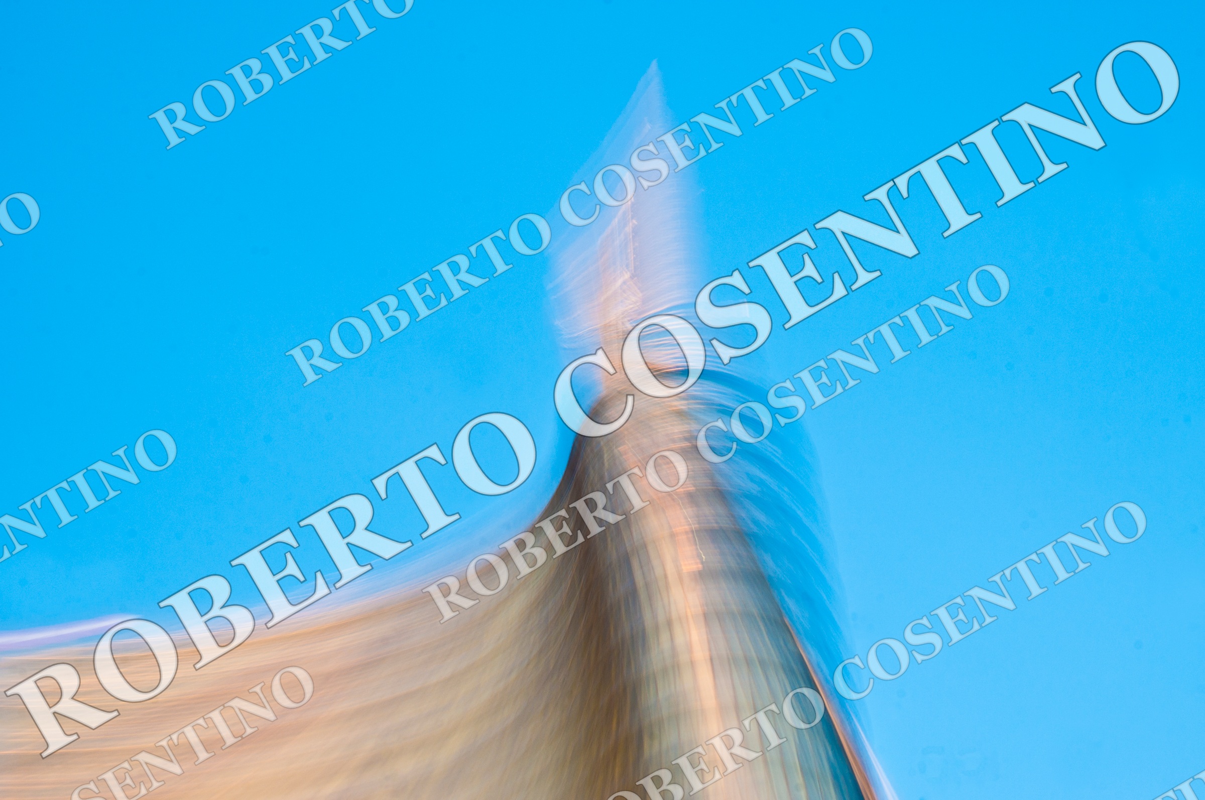 Edificio ripreso dal basso con forte mosso intenzionale contro un cielo azzurro intenso.