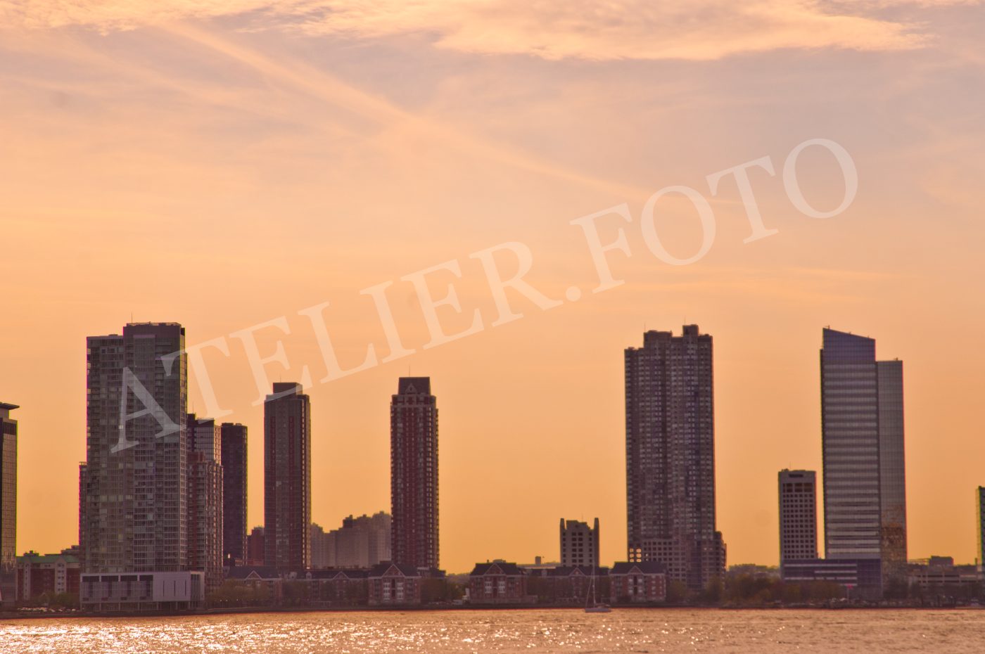 Skyline di grattacieli lungo il waterfront sotto un cielo arancione al tramonto.